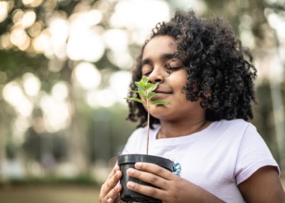 Little Girl in garden, smelling fresh plant